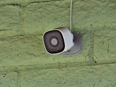 A home security camera is mounted on an outside wall.
